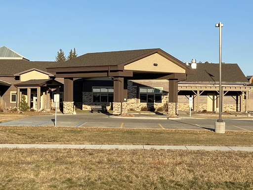 A modern commercial building with a welcoming entrance, surrounded by grass under a clear blue sky.