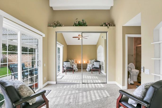 A spacious bedroom with mirrored sliding closet doors and ample natural light.
