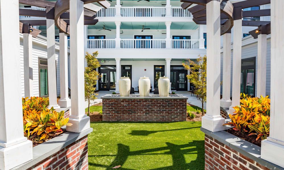A hotel courtyard featuring a fountain and landscaped garden, surrounded by a building with balconies.