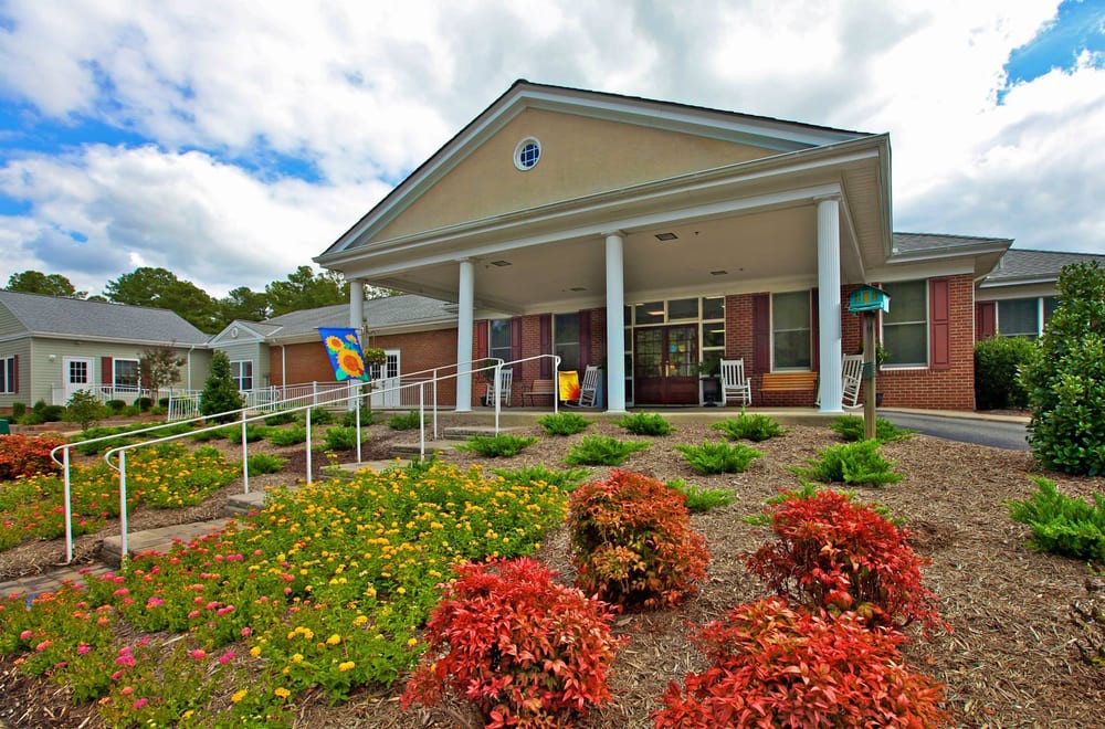 A building with a landscaped garden and columns at the entrance.
