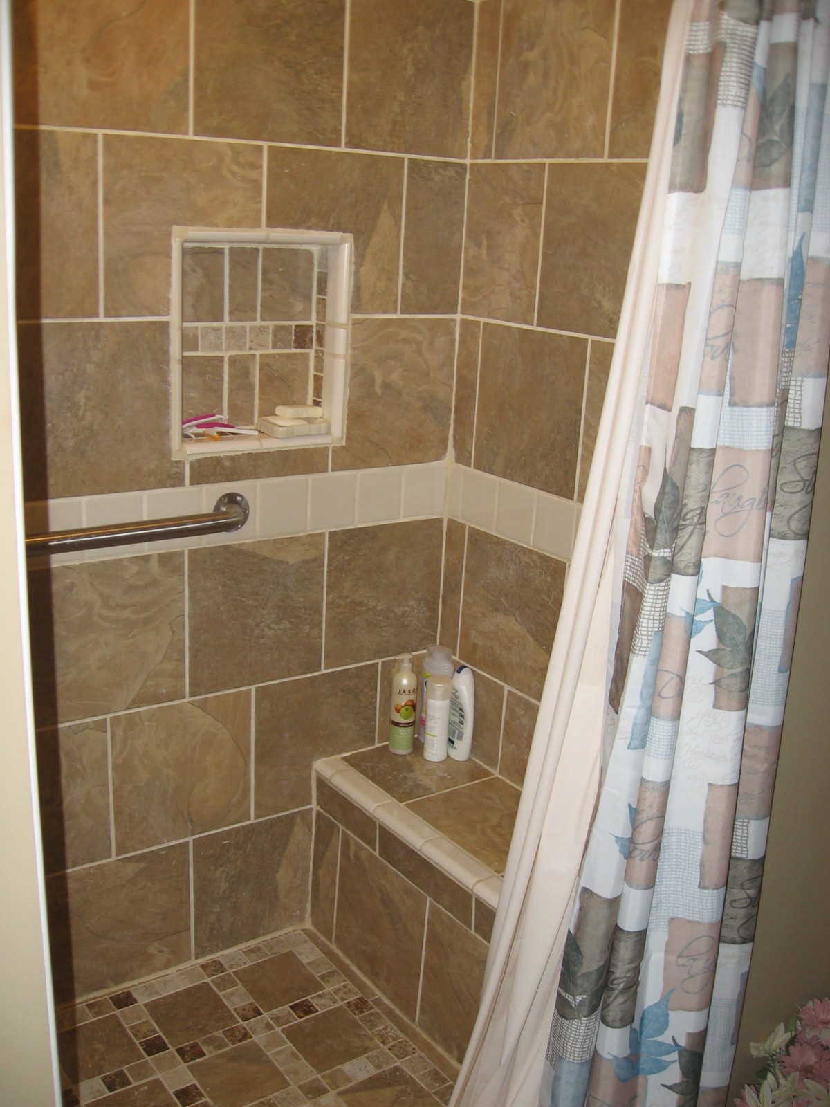 A tiled shower with a corner shelf and curtain.