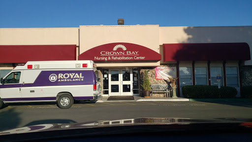 Entrance of Crown Bay Nursing & Rehabilitation Center with an ambulance parked outside.