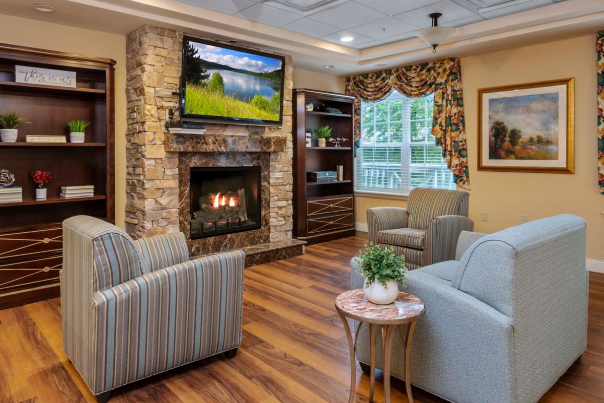 A cozy living room with a stone fireplace, television mounted above, and comfortable seating.