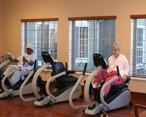 Seniors engaging in physical activity using exercise bikes in a bright and welcoming gym environment.