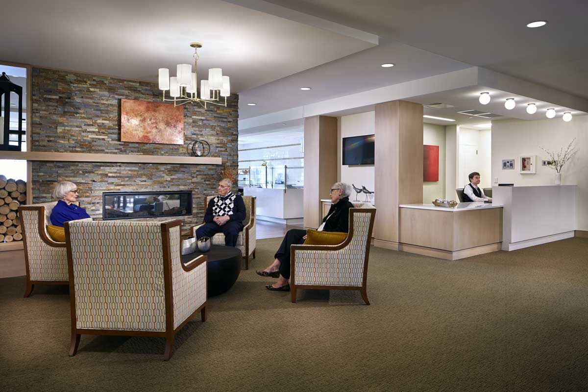 A cozy lobby area with comfortable seating and a fireplace, where people are relaxing and conversing.