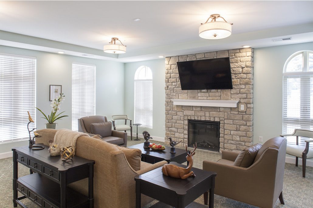 A modern living room with a cozy seating area and a fireplace beneath a wall-mounted TV.