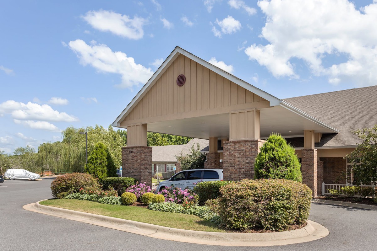 A building entrance with well-maintained landscaping and blue skies in the background.