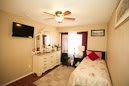 Cozy bedroom with a dresser, ceiling fan, and neatly made bed.