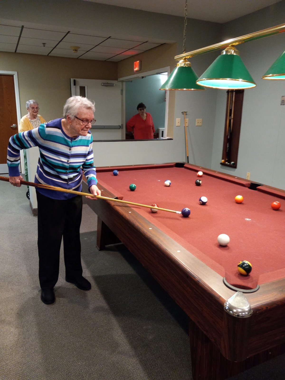 An elderly man playing billiards in a game room.