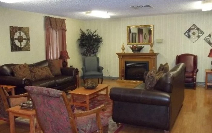 A cozy living room with sofas, chairs, a fireplace, and a mirror on the wall.