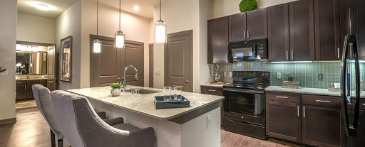 A stylish modern kitchen featuring an island countertop, dark cabinetry, and contemporary lighting.