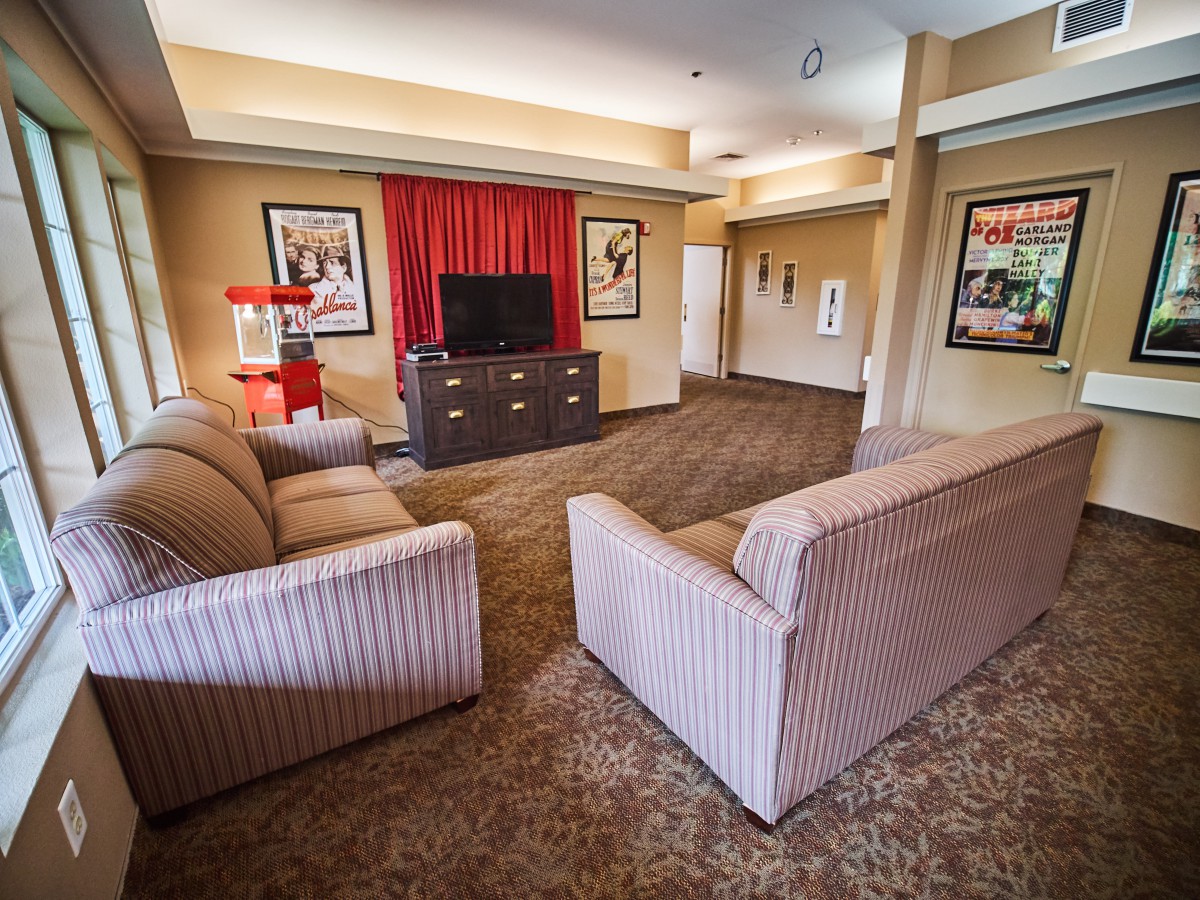 A cozy living room with two sofas facing a TV, adorned with framed artwork on the walls.
