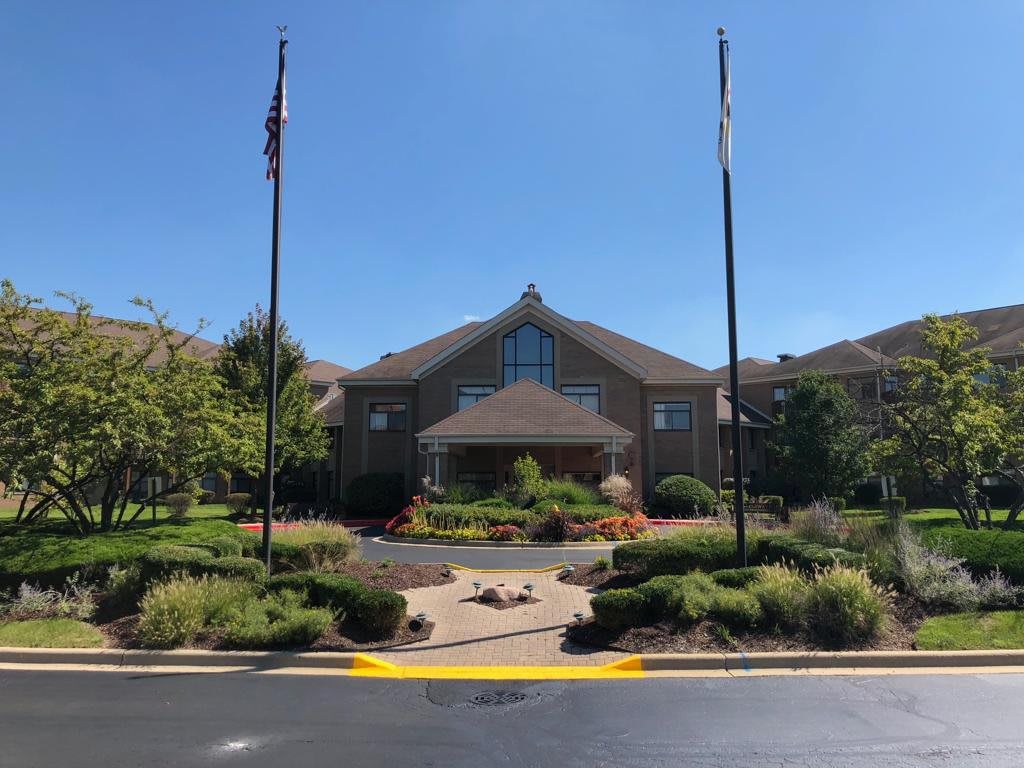 A well-landscaped building entrance with flags on a sunny day.