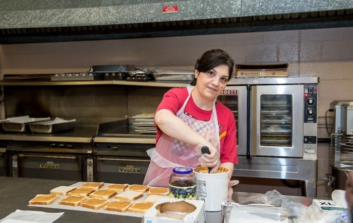 A woman wearing an apron is preparing food in a kitchen.