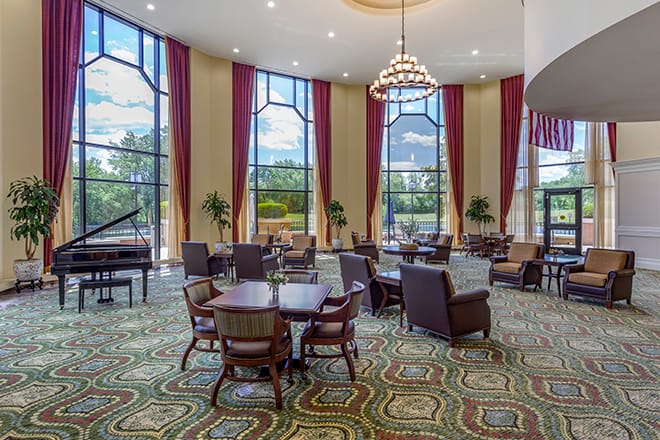A luxurious lobby interior with elegant furniture, large windows, and a grand chandelier.