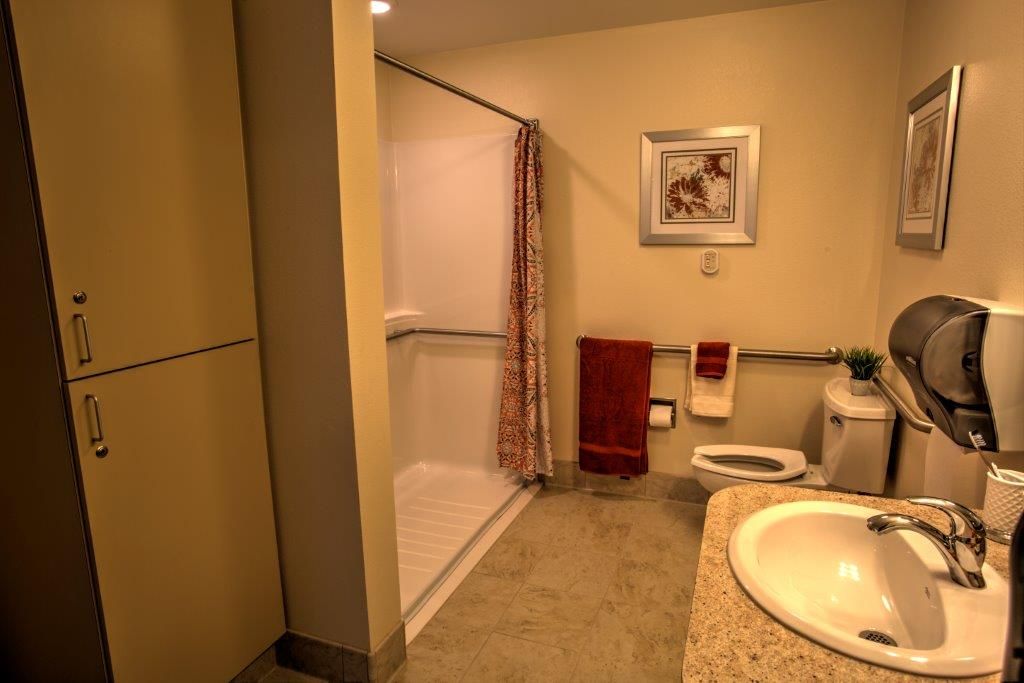 A well-lit bathroom featuring a shower with a curtain, a sink, and a toilet.