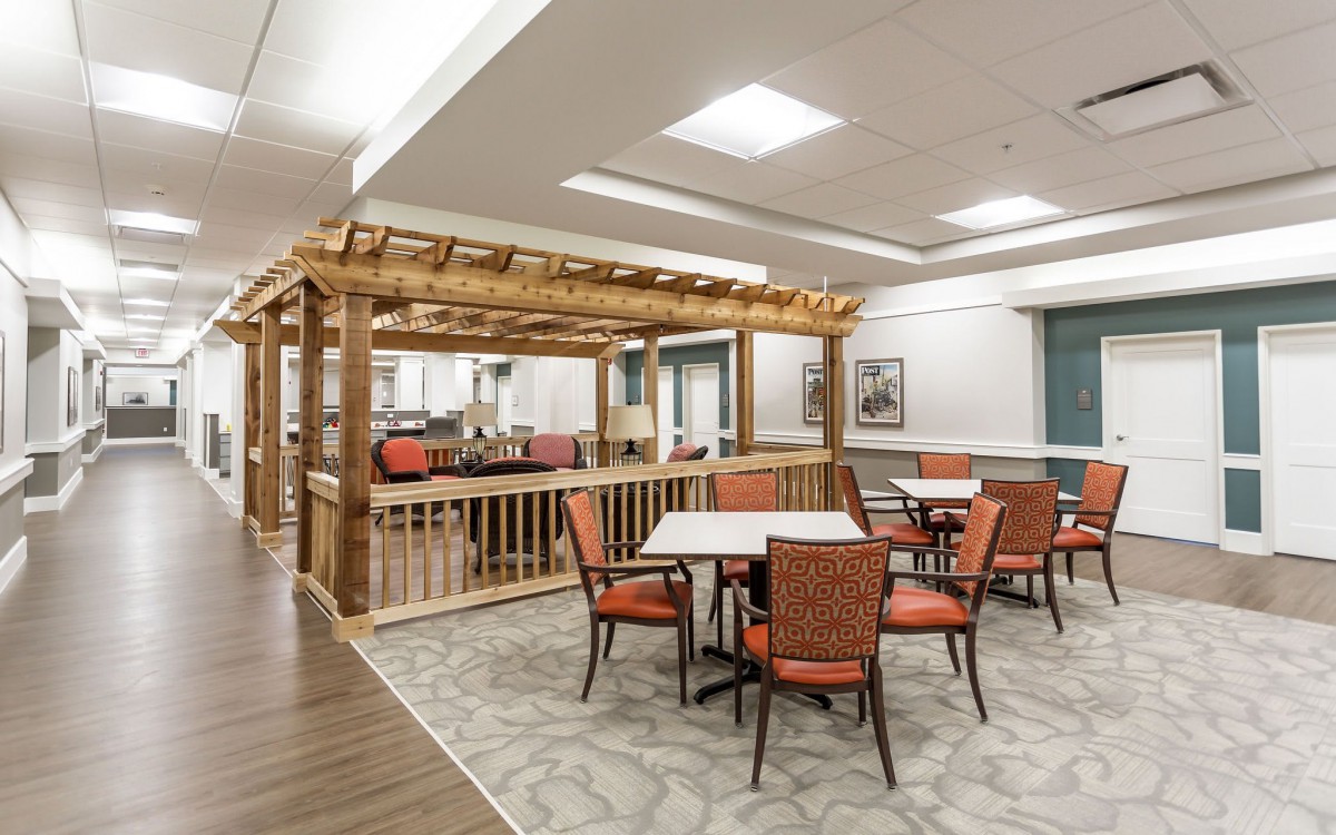 A modern dining area with tables and chairs, featuring a wooden pergola structure.
