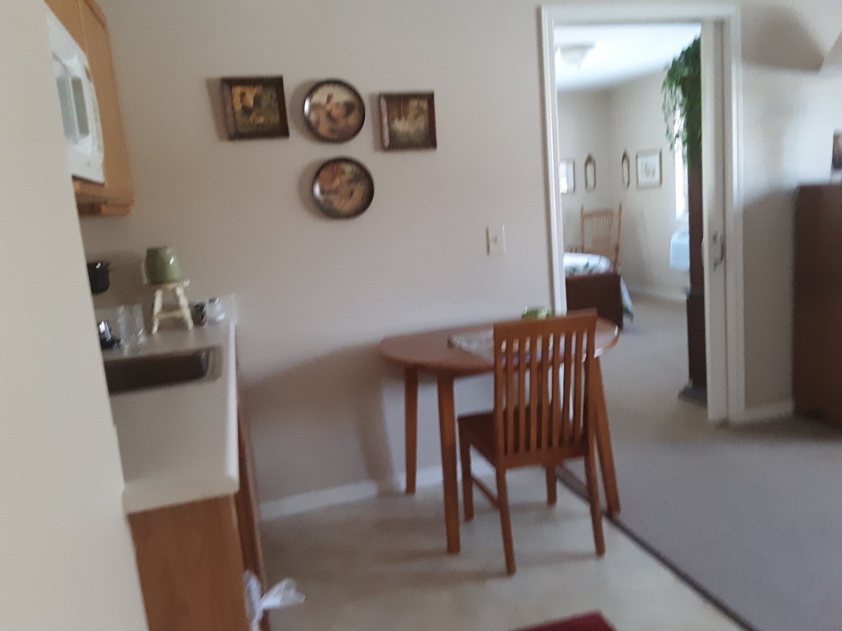 A cozy kitchen and dining area with a small table and chair, decorated with wall art.