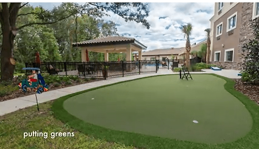 A well-maintained outdoor putting green surrounded by lush landscaping.