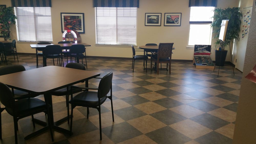 An empty cafeteria with a few tables and chairs, featuring artwork on the walls.