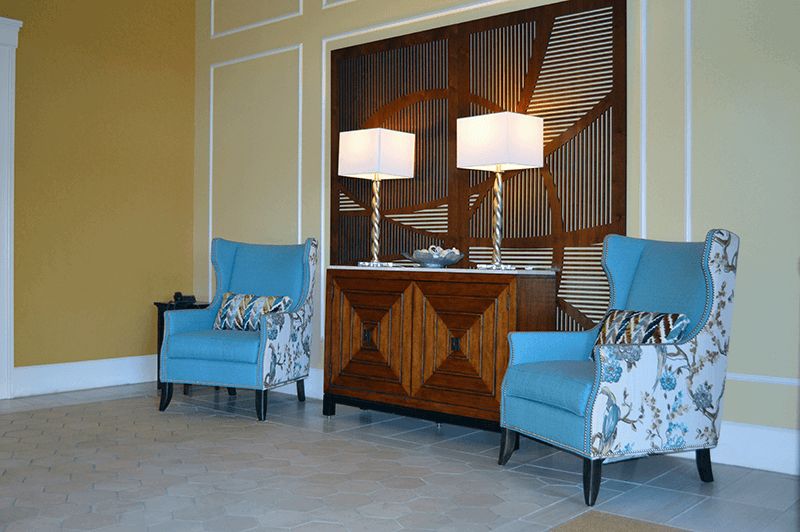 A stylish living room setup featuring blue armchairs, a wooden sideboard, and two elegant lamps.