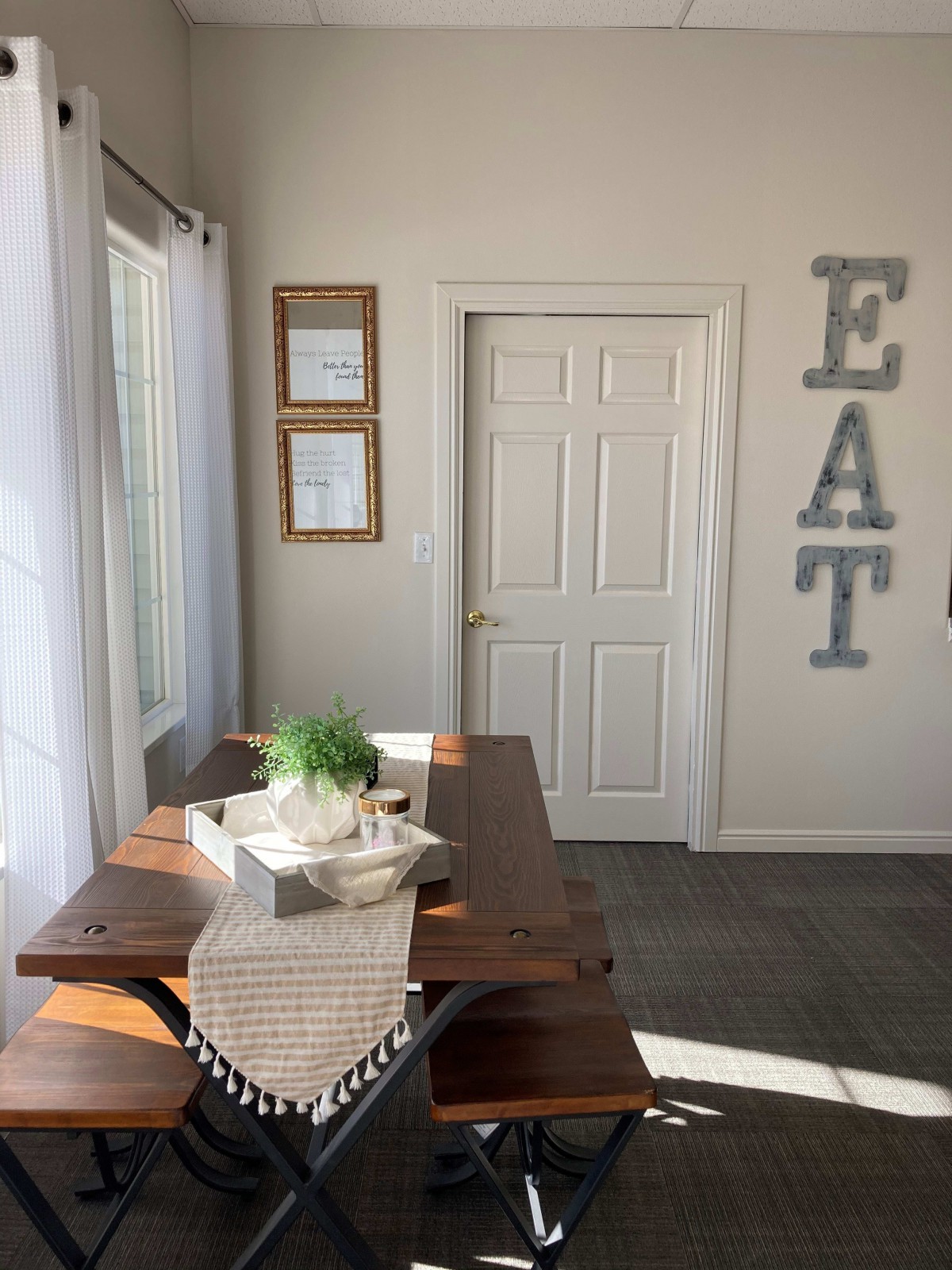 A bright dining area with a wooden table and decorative 'EAT' letters on the wall.