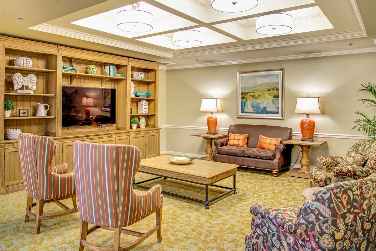 A cozy living room featuring a comfortable sofa, striped chairs, and a wooden bookshelf with decorative items.