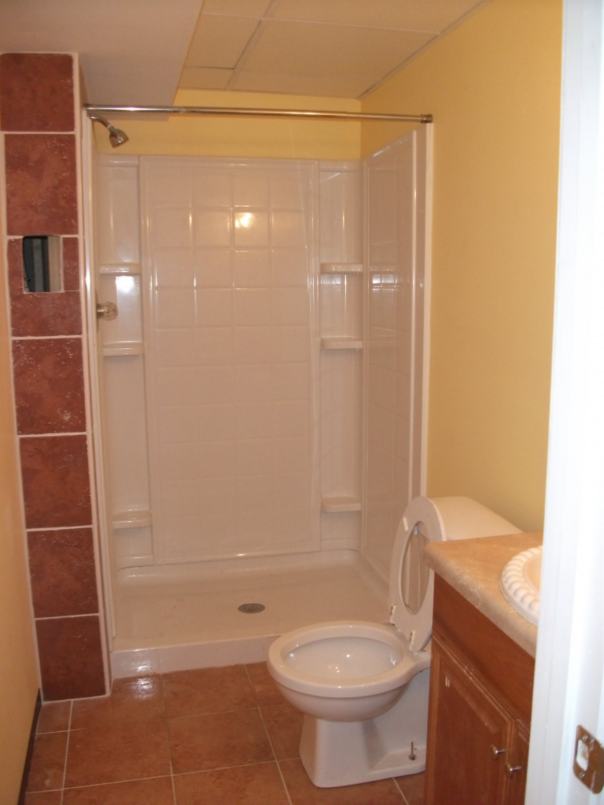 A small bathroom with a shower, toilet, and sink.