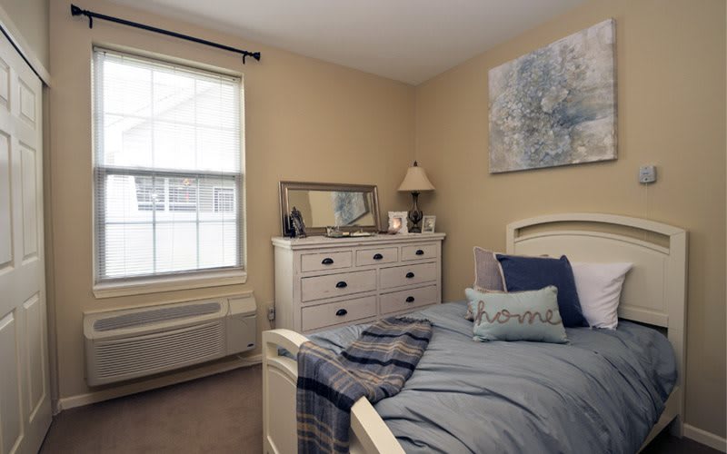 Cozy bedroom with a neatly made bed and a dresser beside the window.