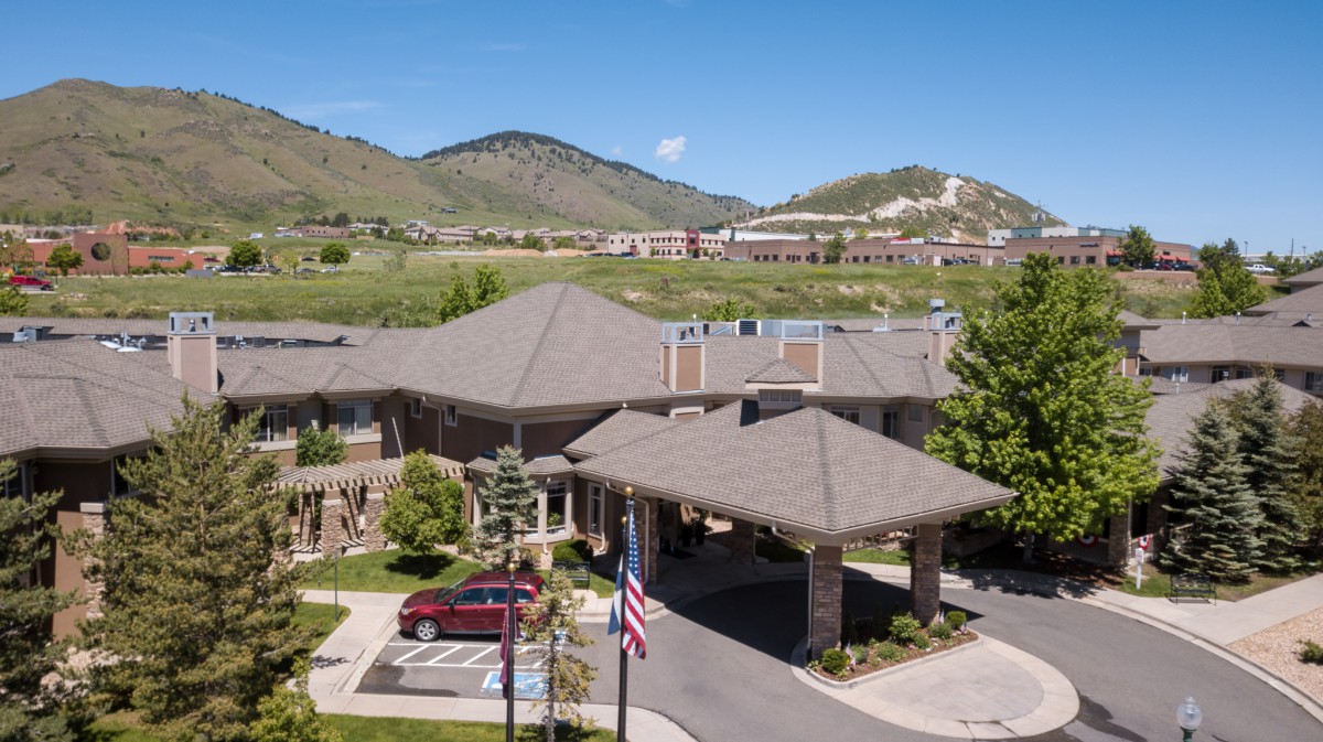 A scenic view of a building nestled in the mountains with a car parked in front and an American flag waving.