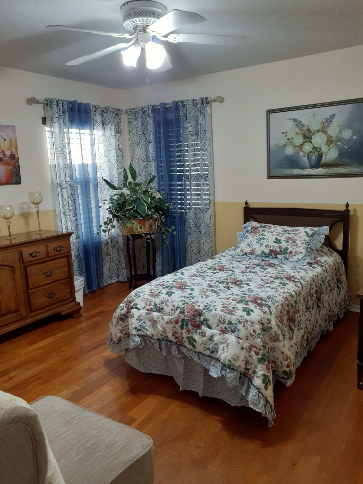 A cozy bedroom with floral bedding and wooden furniture.