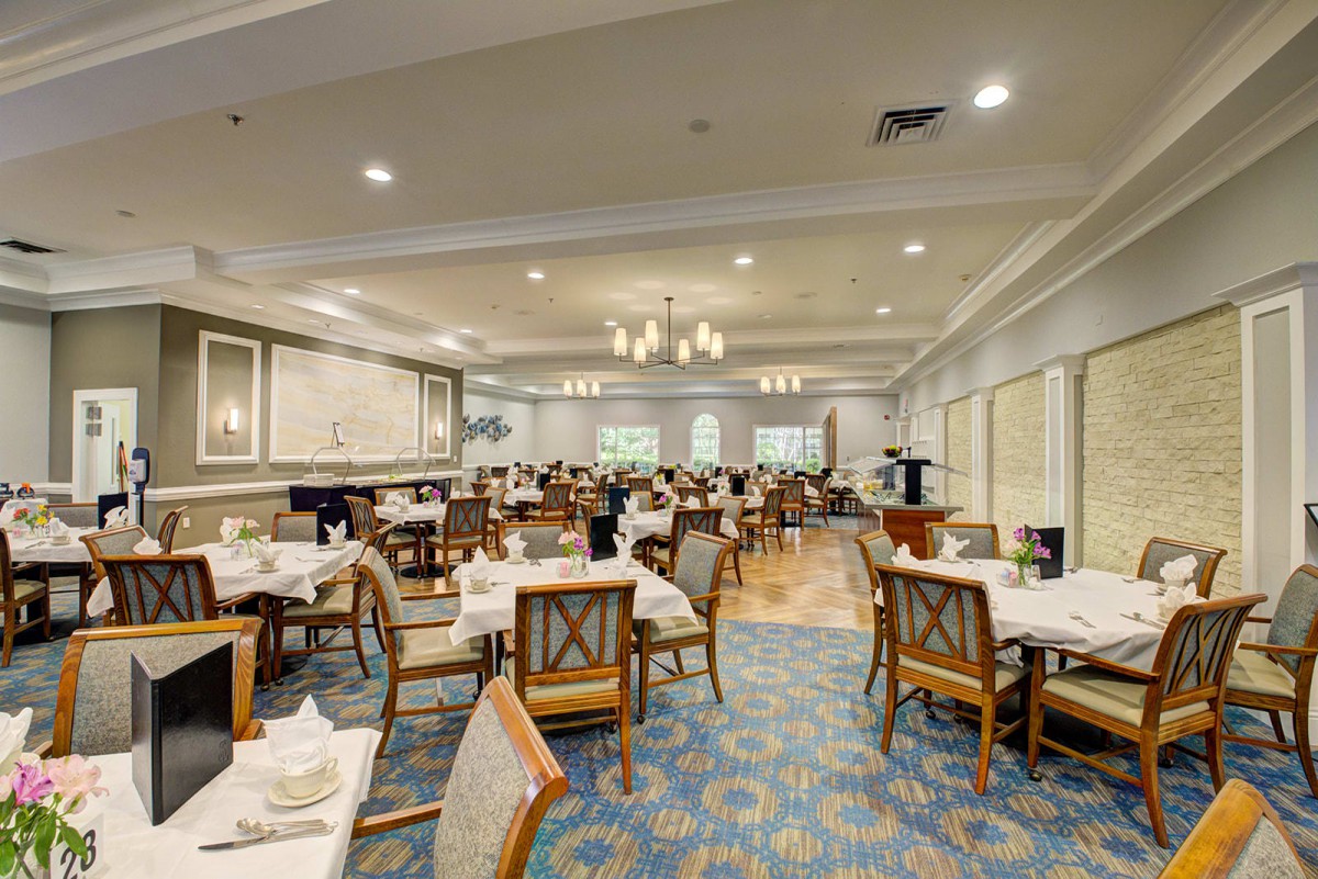 Elegant dining room with neatly arranged tables and chairs under a chandelier.