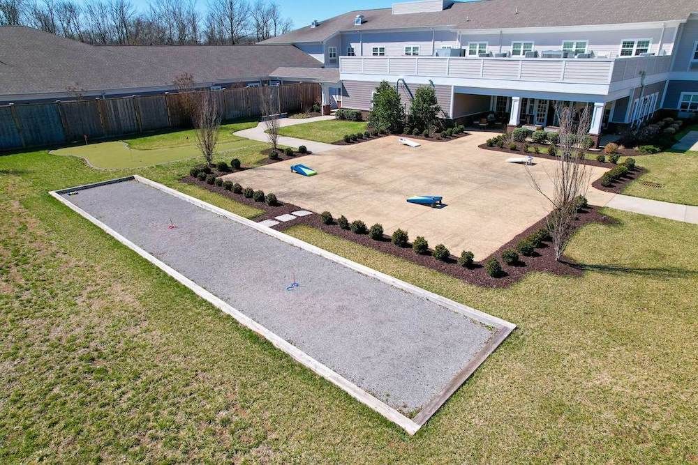 A landscaped courtyard with a paved path and neatly arranged shrubs in front of a modern building.