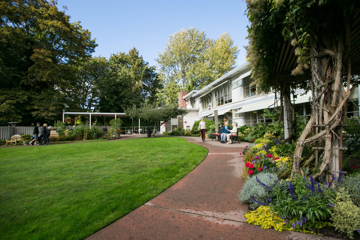 A charming house surrounded by a well-maintained garden with lush greenery and colorful flowers.