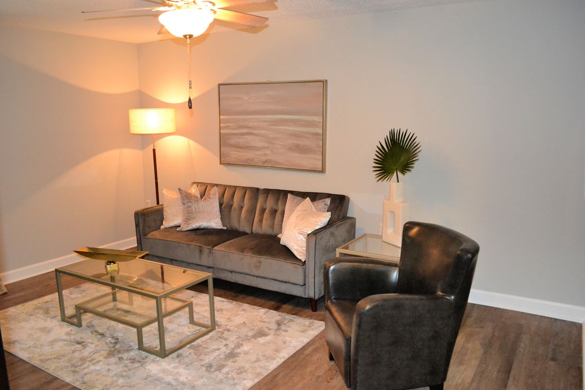A modern living room featuring a gray sofa, black armchair, glass coffee table, and stylish decor.