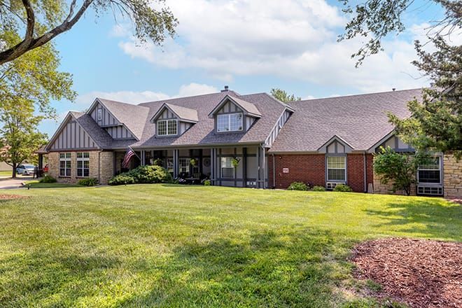 A spacious residential house with a well-maintained lawn and clear skies.