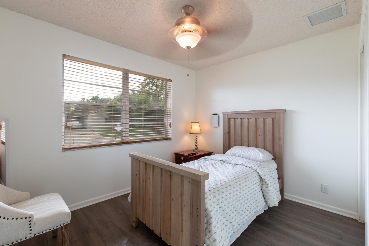A minimalist bedroom featuring a single bed, wooden furniture, and a warm lamp by the window.