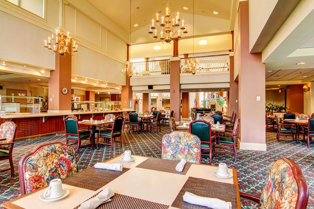 A spacious dining area in a restaurant with neatly arranged tables and elegant chandeliers.