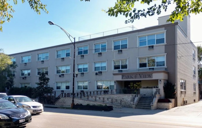A residential apartment building on an urban street with parked cars.