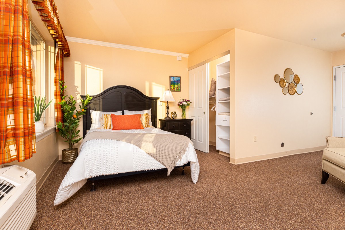 A cozy bedroom with warm lighting and stylish decor, featuring a comfortable bed, nightstand, and indoor plants.