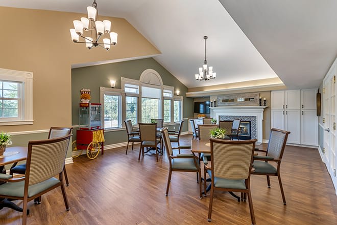 A spacious dining room with elegant chandeliers, wooden flooring, and a fireplace.