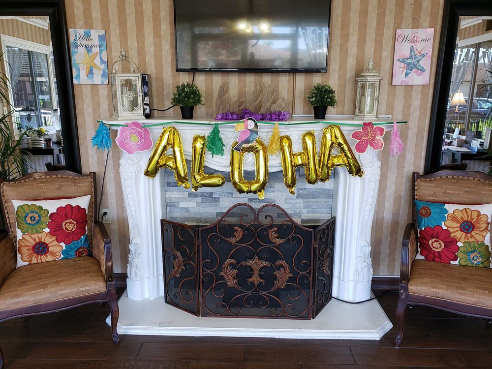 A fireplace decorated with 'ALOHA' balloons and tropical-themed decorations, setting a Hawaiian party atmosphere.