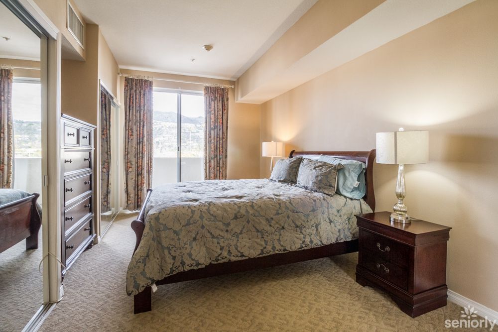 A cozy bedroom with a large bed and nightstands, lit by natural light through the window.