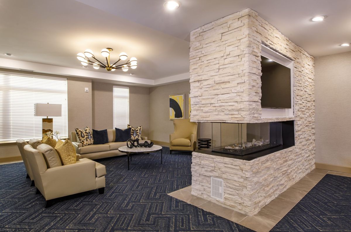 A modern living room featuring a central fireplace with comfortable seating and contemporary lighting.