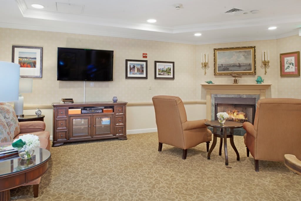 A cozy living room with a television, comfortable chairs, and a fireplace.