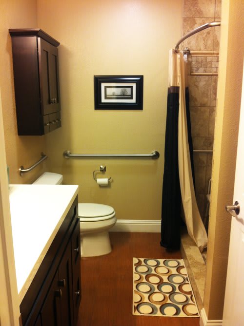 A small, neatly organized bathroom with a shower curtain and wall art.
