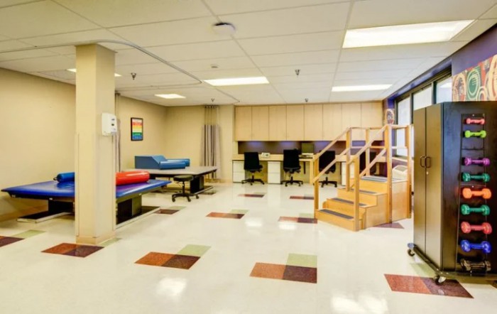 A rehabilitation room with exercise equipment and therapy stations.