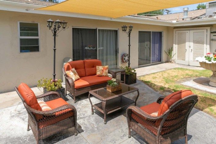 A cozy patio area with outdoor seating and a shade sail in the backyard.