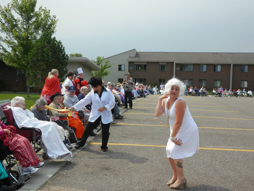 A lively outdoor event with performers in costume entertaining a seated crowd.