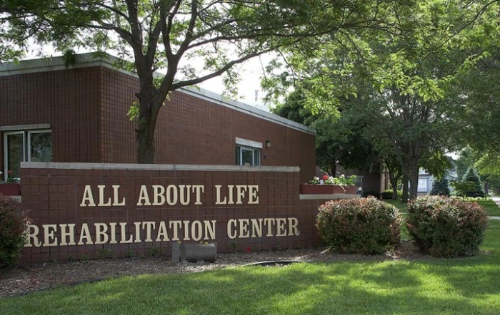 A view of the All About Life Rehabilitation Center with surrounding trees and landscaping.